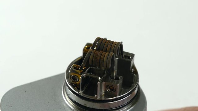 Vaping atomizer with clapton coil is working on a white background.