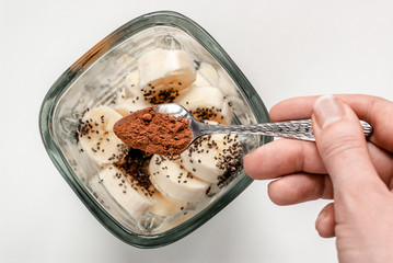 Ingredients for smoothies. Bananas, chia seeds and cocoa powder in a blender on a white background.