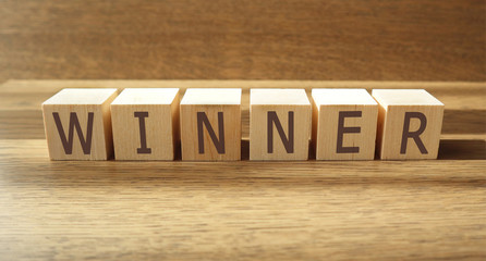 WINNER word made of wooden cubes on a brown background, business concept. Banner.
