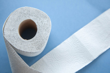 Unwinding toilet paper on a blue background. toilet paper deficiency coronovirus
