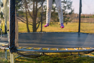 Little girl jumping on the trampoline in the back yard. Teenager bouncing on the trampoline