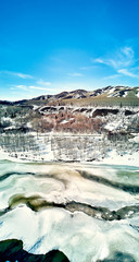 Panoramic aerial view: beautiful spring landscape: the Ulba river in Kazakhstan wakes up from winter sleep - ice drift - snow and ice are melting in the mountains, the bright sun is shining