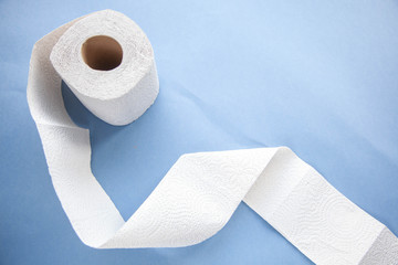 Unwinding toilet paper on a blue background. toilet paper deficiency coronovirus
