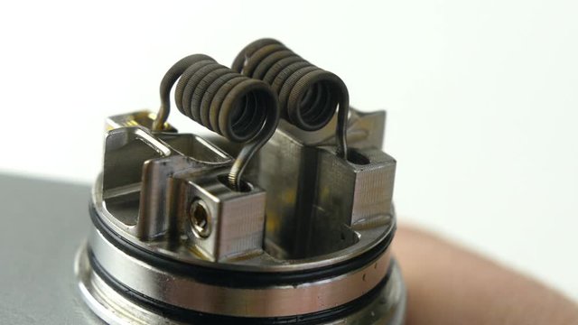 Vaping atomizer with clapton coil is working on a white background.