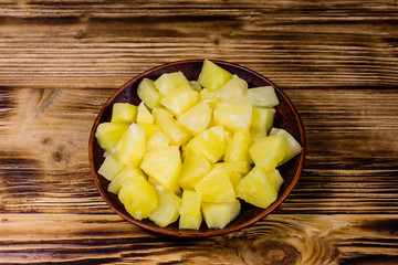 Ceramic plate with chopped canned pineapple on wooden table