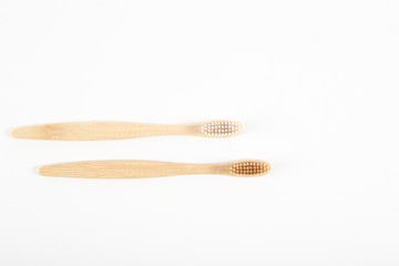 Two toothbrushes made of natural ecological wood designed for cleaning teeth, on a white background.