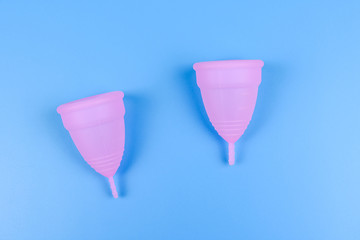 Pink menstrual cups isolated on a blue background. Woman hygiene