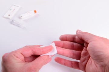 Blood test woman taking blood sample using sterile alcohol wipe on finger closeup isolated on white