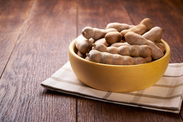 tamarind  in a wooden bowl on a wooden table.
