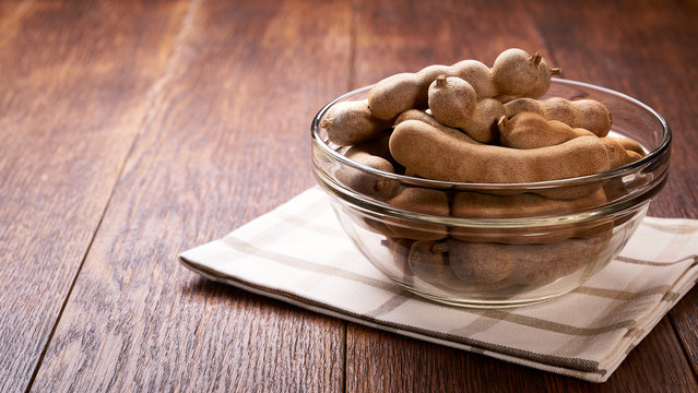 tamarind  in a transparent glass bowl on a wooden table.