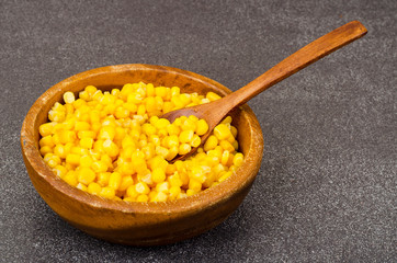 Sweet ripe canned corn in wooden bowl.