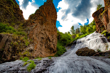 waterfall and rock with trees aunder sky