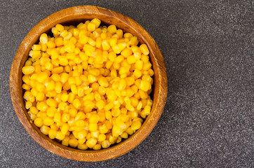 Sweet ripe canned corn in wooden bowl.