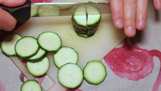 hands of a man who cuts some slices of zucchini