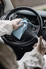 Cleansing car interior and spraying with disinfection liquid. Hands in rubber protective glove disinfecting 
steering wheel for protection from virus disease. Pandemic сoronavirus protection сoncept.