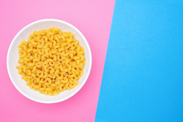Italian pasta cavatappi in a white medium bowl on a colored background with space for text. Top view.