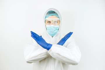 Fototapeta na wymiar Doctor in a medical mask, overalls and blue gloves on a white background. Stop the Covid 2019 epidemic. Doctor shows stop sign with his hands.
