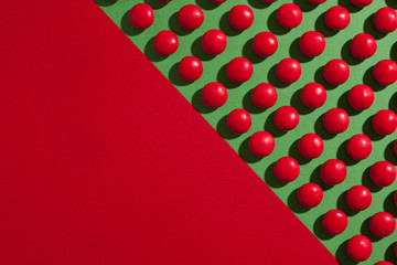 Red round chocolate candies on a green background with copyspace. Top view.