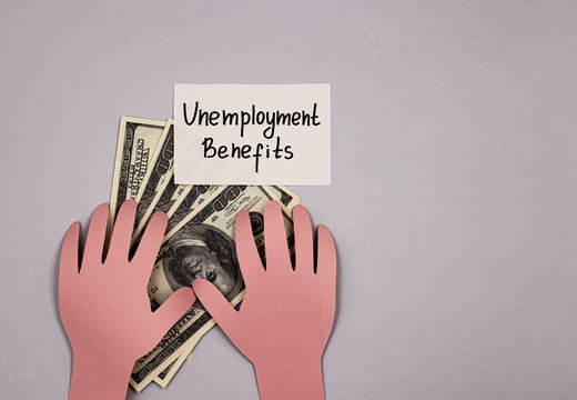 hands of paper holding money and the inscription unemployment benefit. the concept of issuing insurance benefits to people who lost their jobs due to covid-19