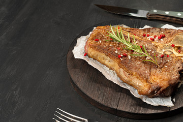 Top view of grilled t-bone steak with spices on black table