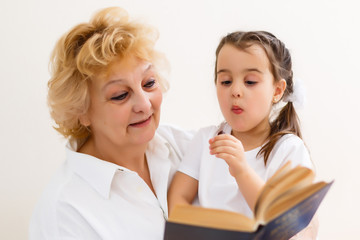 Obraz na płótnie Canvas little girl with grandma reading interestng book
