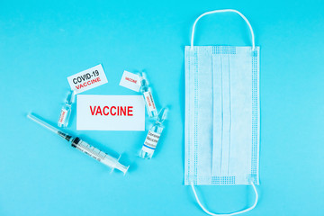 coronavirus vaccine testing. Vials with medicines, pills, syringes, thermometer, medical mask on a blue table. a cure for seasonal flu and the common cold. Means for the treatment of covid-19