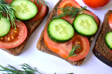 Several diet sandwiches with cucumber and tomato from black bread