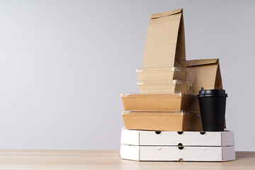 Many various take-out food containers, pizza box, coffee cups and paper bags on light grey background. Food delivery
