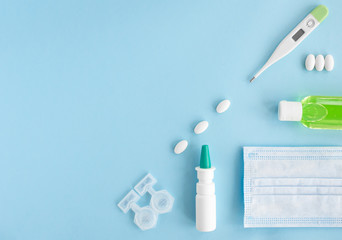 Flat lay with set of medication, thermometer, pills, face mask, sanitizer, spray. Treatment of flu and colds. Top view of the medicine on blue background, copy space