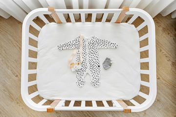 The top view of baby clothes and accessories in cot, cradle. Wooden cradle for newborn  in baby's...