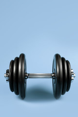 Professional dumbbell and weight plates over blue background. Gym equipment. Fitness concept.