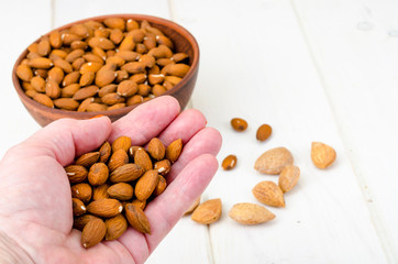 Peeled and unpeeled almonds on wooden background.
