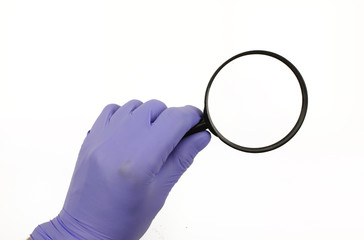 Hand holds a magnifying glass.