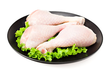 Raw chicken legs on black plate isolated on white background
