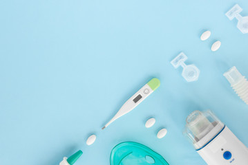 Flat lay with set of medication, thermometer, pills, inhaler, spray. Treatment of flu and colds. Top view of medicine on blue background, copy space