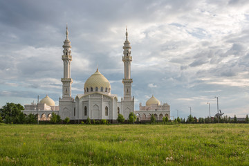 Fototapeta na wymiar Beautiful white mosque in the city of Bulgar on the background of a beautiful sky with a green meadow in the foreground