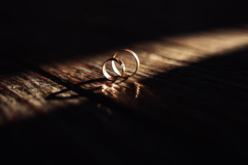 wedding rings in sunlight on wooden surfaces.