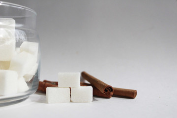 Cinnamon sticks and sugar chunks in a jar on a white background isolate