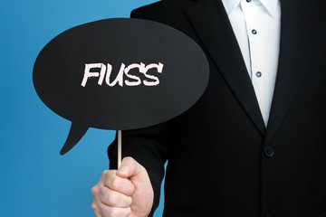 FIUSS. Geschäftsmann im Anzug hält Sprechblase in die Kamera. Der Begriff FIUSS steht im Schild....