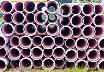 Large plastic pipes are stacked creating an abstract pattern while waiting to be installed under ground.