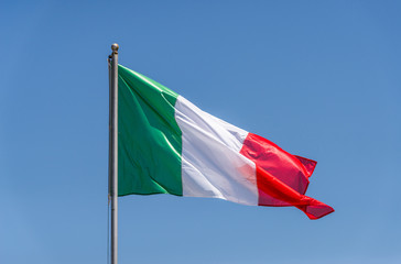Italian flag waving against blue sky on a sunny day