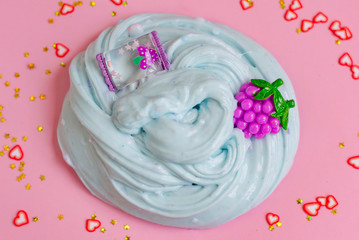 close up hand made toy called slime and accessories for decoration. blue slime on pink background
