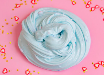 close up hand made toy called slime and accessories for decoration. blue slime on pink background
