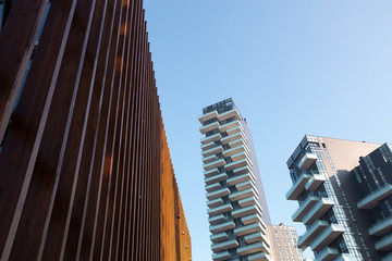Unusual wooden structure against the backdrop of a metropolis with high-rise buildings against the blue sky. 01.2020 Milan