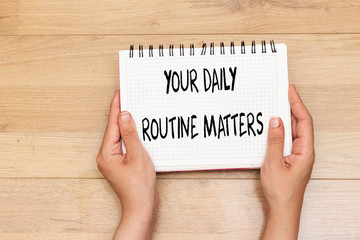 hands holding notebook with  Your Daily Routine Matters concept for practice of regularly 