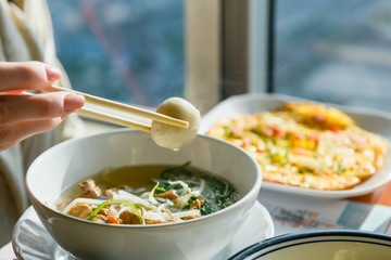Hand with chopsticks hold ball from soup