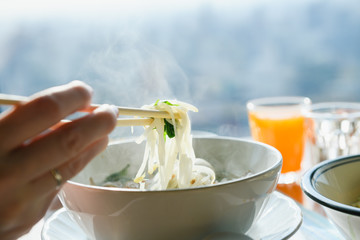 Female hand hold chopsticks with rice noodles