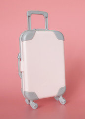 Pink suitcase for vacation on a pink background. For traveling with luggage on an airplane, car or sea transport.