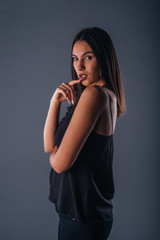 Sensual studio portrait of a sexy woman standing with one arm crossed on a gray background