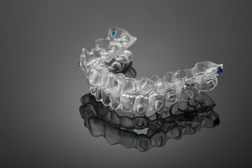 Invisible orthodontics cosmetic brackets on black background, tooth aligners, plastic braces. A way...